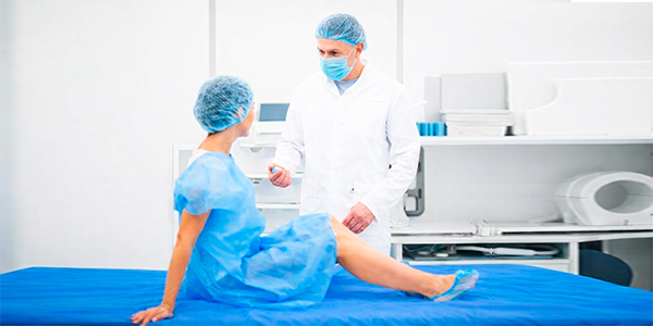 Paciente con ropa desechable: cofia, gorro, cubrebocas, cubrezapatos, sábana y bata.